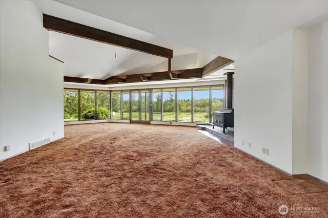 The grand vaulted room boasts a ceiling with an exposed beam and a wall of windows that fills the space with abundant natural light.