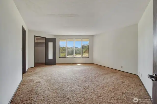 Another primary bedroom #3 is located at the opposite end of the home. Bedroom #3 is spacious. In this photo, the walk-in-closet and 4 vertical windows. Not viewable is the en-suite bath.