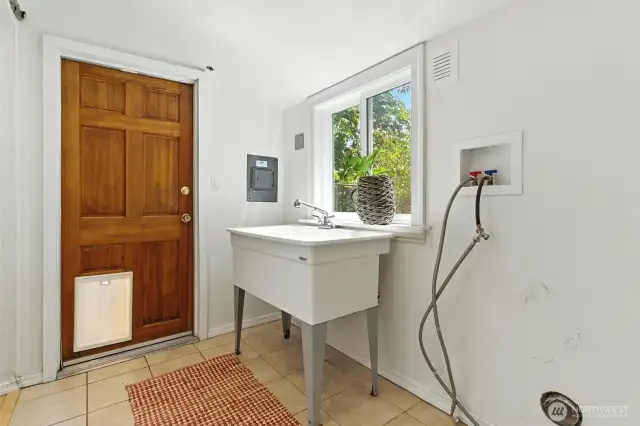 Utility room off of kitchen with door to small fenced dog area at front of house