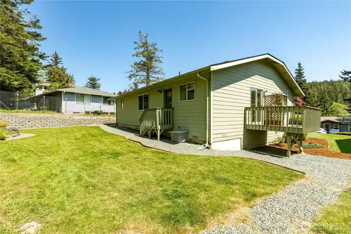 More back yard showing door off Kitchen, gravel area for BBQ and Deck off Dining area.