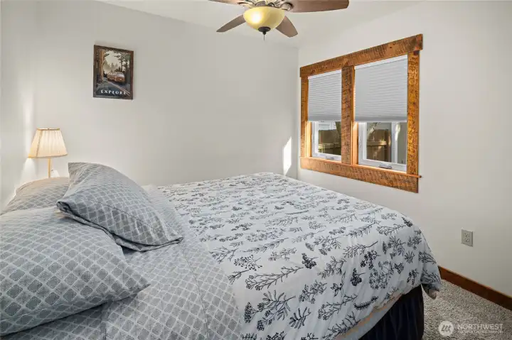 View of one of the main floor bedrooms w/ a fan for fresh air. Stunning reclaimed wood for window trim.