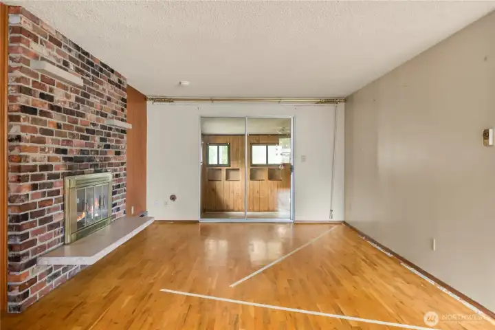 As you enter, the newly uncovered original hardwood flooring shines in the living area. Wood-burning fireplace with brick surround makes a statement.