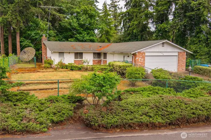 View of the home from the street - surrounded with mature shrubs and fencing - the privacy is abundant.