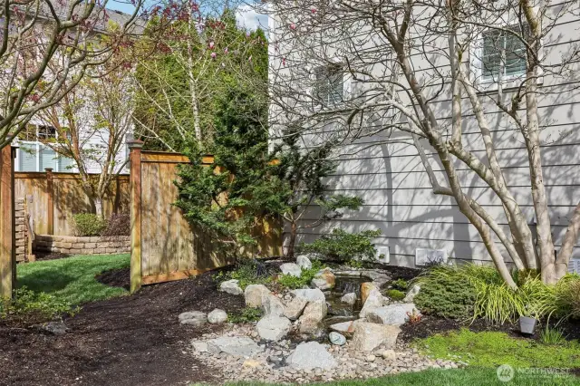 Beautifully landscaped yard includes a sprinkler system and custom water feature