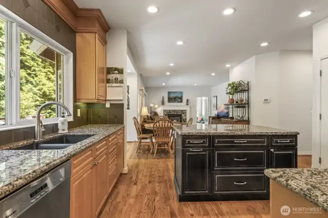 The informal areas are one contiguous space and feature an updated kitchen with maple cabinets with soft close drawers and doors, slab granite counters, an island with seating, stainless steel appliances including a gas range and a walk-in pantry.