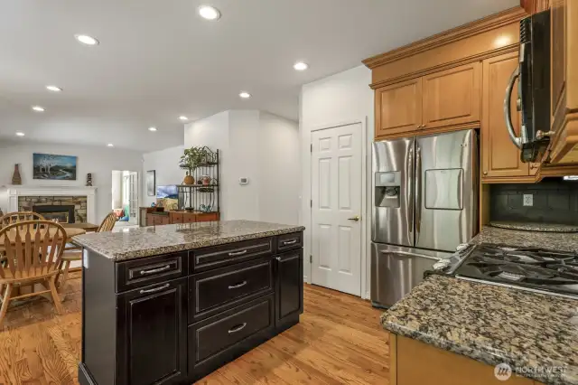 The informal areas are one contiguous space and feature an updated kitchen with maple cabinets with soft close drawers and doors, slab granite counters, an island with seating, stainless steel appliances including a gas range and a walk-in pantry.