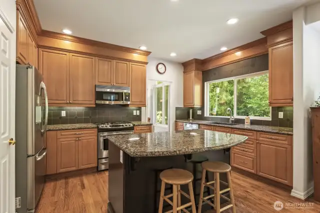 The informal areas are one contiguous space and feature an updated kitchen with maple cabinets with soft close drawers and doors, slab granite counters, an island with seating, stainless steel appliances including a gas range and a walk-in pantry.