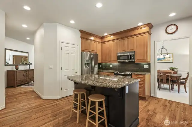 The informal areas are one contiguous space and feature an updated kitchen with maple cabinets with soft close drawers and doors, slab granite counters, an island with seating, stainless steel appliances including a gas range and a walk-in pantry.