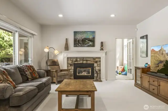 The informal gathering room features a stone surround gas fireplace and sliding door to the deck.
