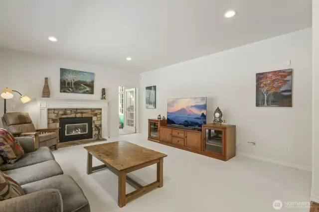 The informal gathering room features a stone surround gas fireplace and sliding door to the deck.