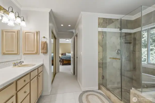The primary suite with crown molding and tranquil backyard views features 2 walk-in closets and an updated 5 piece bathroom with soaking tub, tiled shower, dual vanities and tile floor.