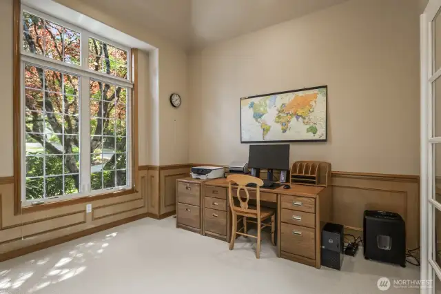 French doors lead into the office that features  wood wainscoting.