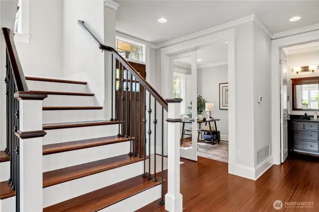 Stairs lead to the upper level. The home office in the background. Not pictured is the main floor powder room.