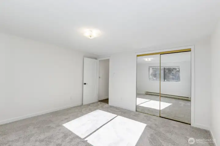 Another view of bedroom reflecting full length mirrored closet doors.