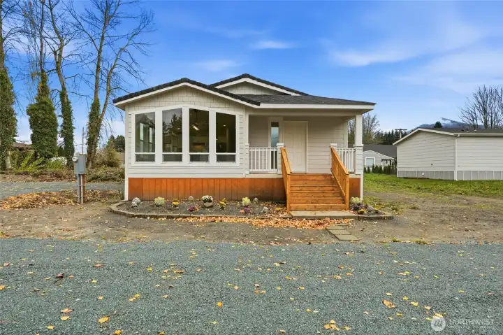 Front view showcasing the large picture windows that fill the home with natural light and a welcoming covered entry.