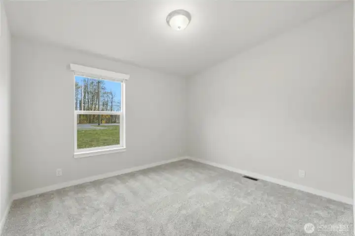 This photo showcases the third bedroom, which features comfortable carpeting and a generally cozy vibes.