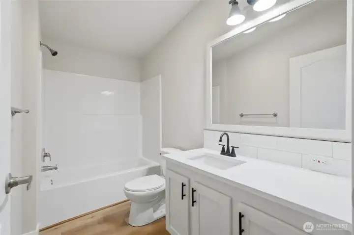 The full bathroom features a contemporary vanity design and utilizes a palette of clean, modern tones throughout the space, creating a fresh feel.