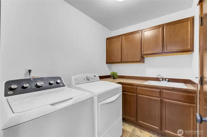 laundry conveniently located off garage with utility sink and cabinets for storage