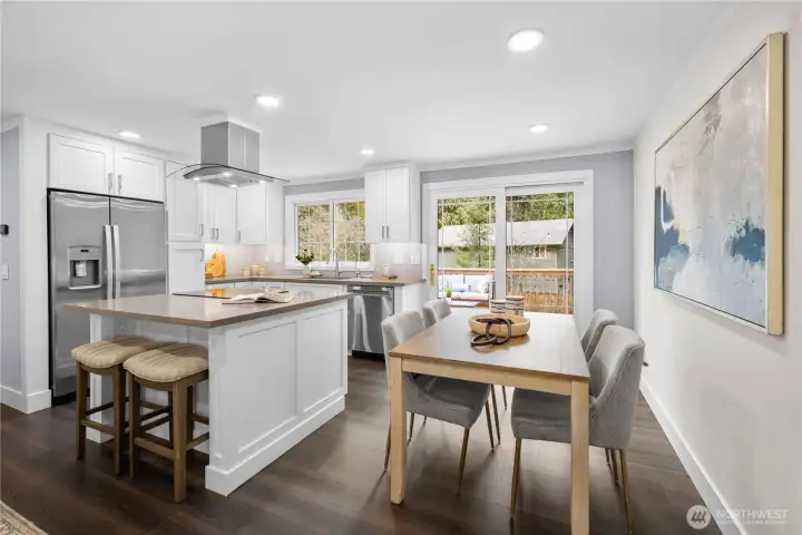 Sliding glass doors extend the dining area outward to the large deck, blending indoor and outdoor living with ease. The glass panels are accented with clean lined grilles that add subtle architectural detail while maintaining a modern aesthetic. A warm brushed metal handle adds a refined, contemporary touch against the crisp white frame. With southern exposure, the expansive glass bathes the dining area in natural light throughout the day and soft sunset glow in the evenings, bringing warmth and atmosphere to dinnertime. Beyond the glass, mature trees and open sky create a lush, natural backdrop that makes every meal feel connected to the living landscape outside.