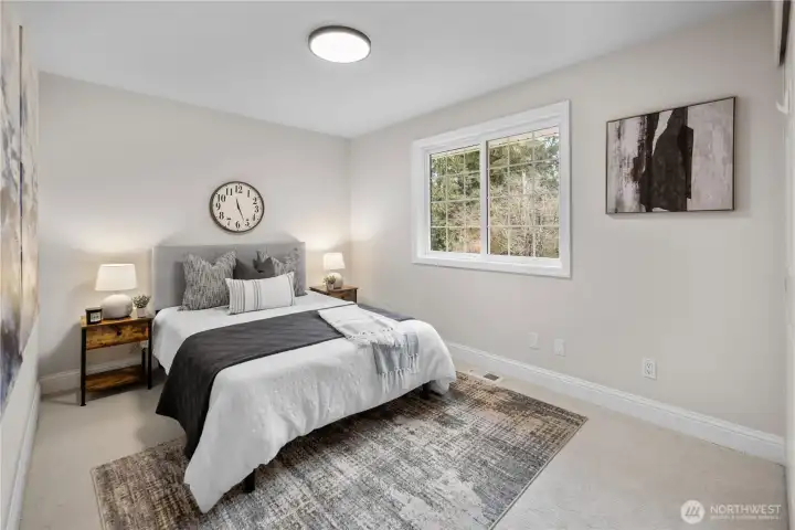 This upstairs bedroom offers a calm, spacious, comfortable retreat with fresh paint in warm, light tones that brighten the space while keeping it soft and inviting. The neutral palette pairs beautifully with the brand new carpet, its natural hue creating a versatile foundation that works effortlessly with any style or color scheme.   A generously sized closet provides excellent storage, keeping the room open and uncluttered. The window is framed with crisp white trim and classic multi-paned detailing, giving it a tailored presence that quietly anchors the room. The large window welcomes in abundant natural light throughout the day, with peaceful treetop views adding a quiet connection to the outdoors.  Overhead, a new modern ceiling fixture adds a clean, updated touch, casting even, flattering light that complements both daytime brightness and evening relaxation. The result is a bedroom that feels refreshed, cohesive, and ready to make your own.