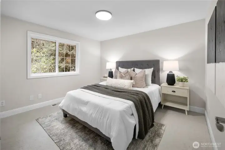 This second upstairs bedroom also carries the same fresh, cohesive feel, generously large, and wrapped in newly painted soft neutral tones that reflect light beautifully throughout the day. Brand new carpet adds a quiet layer of comfort underfoot, its natural coloring blending seamlessly with a wide range of furnishings and styles.  The classic multi-pane window, framed in crisp white trim, welcomes in gentle daylight and a peaceful view of the evergreens beyond. A spacious closet keeps storage simple and organized, and the modern ceiling light offers a clean, contemporary glow that completes the room’s bright, inviting finish.