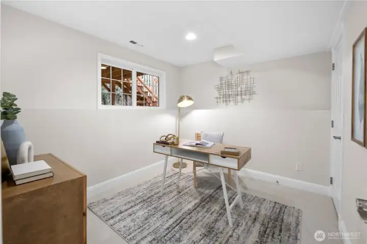 This fourth bedroom carries the same cohesive palette found throughout the home, with fresh paint in soft, welcoming tones and new carpet in a versatile natural shade. The color story keeps everything feeling calm and connected from room to room.  A wide, multi-paned window brings in natural light, adding brightnes and giving the space an open, comfortable presence throughout the day.   Updated recessed lighting casts an even, gentle glow across the room, keeping evenings bright and welcoming while maintaining the same understated style found throughout the home.