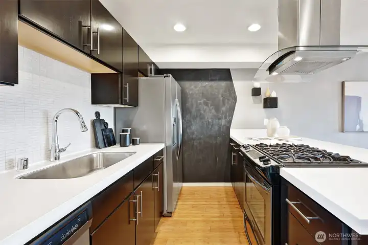 The kitchen features stainless appliances, gas cooking, Quartz counters, a stylish vent hood and blackboard wall.