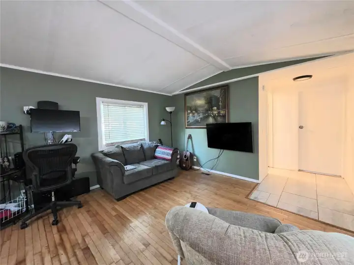 Laminate floors in the living room and tiled entry. To the right is one of three bedrooms.