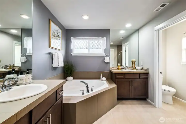 Spa-inspired primary bath featuring dual vanities, a soaking tub, and a separate shower.