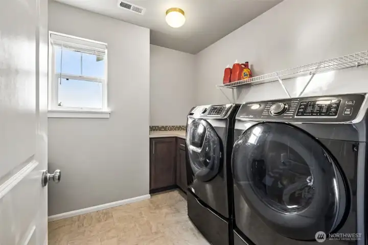 Dedicated laundry room with storage and counter space for added convenience.
