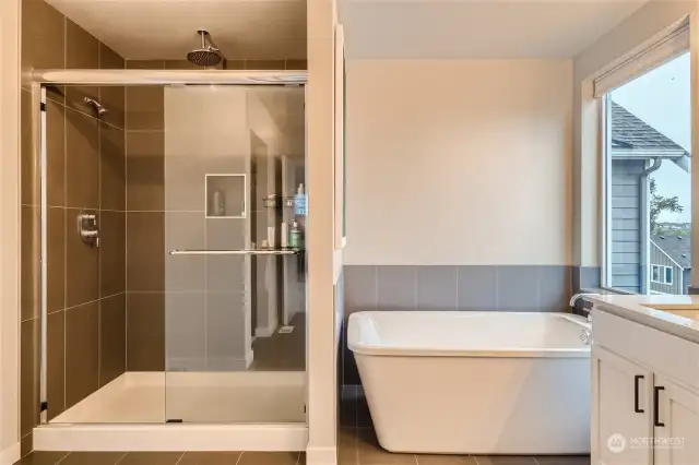 Large walk in shower features a rain shower head and two wall mount shower heads.
