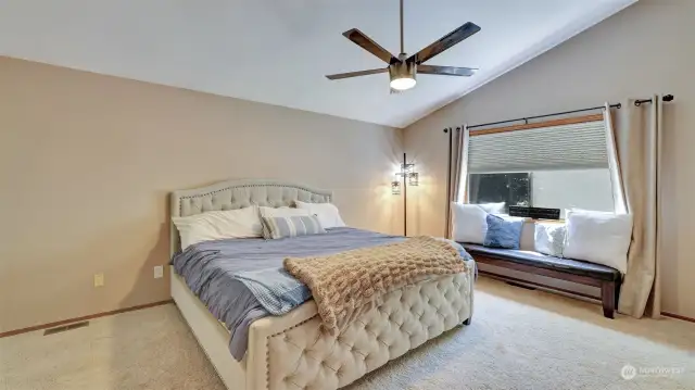 Spacious primary bedroom with dramatic vaulted ceilings.