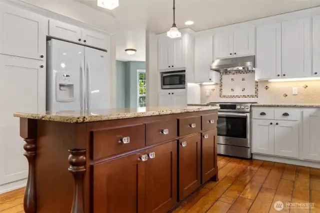 Large kitchen island boasting high quality granite countertops, with plenty of storage and pull out trash.