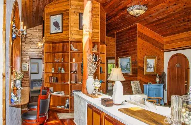 Built-in bookcases in middle - brick structure with storage to right had previously had bookshelves and housed plants by a previous owner. Kitchen bar in foreground and guest room at end across hallway