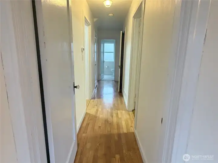 Hallway off of living room leads to bedrooms, a full bathroom, and basement access