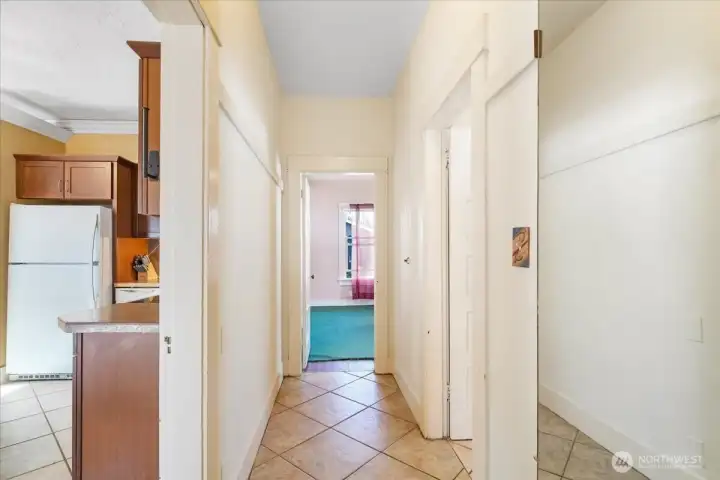 Tiled hallway, with linen closet, leading to 2 large bedrooms and the bathroom.