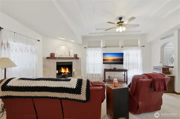 Living room with gas log fireplace and multi-level ceiling.