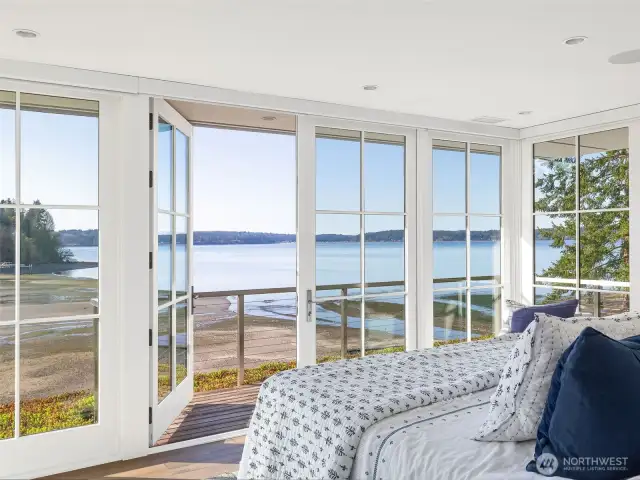 In the private, luxurious primary suite, corner walls of glass open to a wraparound deck—an extension of the room itself. The tide is out in this photo!