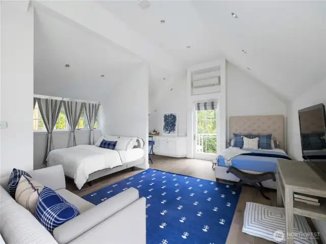 The second primary suite, located in its own private wing and accessed by a private staircase, features vaulted ceilings, a large sitting area, kitchenette, ¾ bathroom, and a balcony overlooking the lush green yard and gardens.
