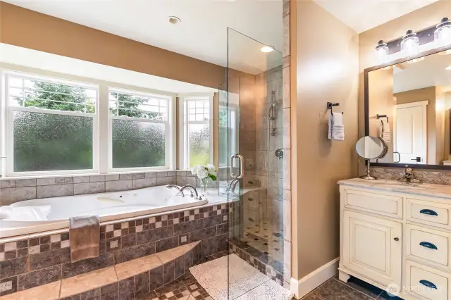 Jetted soaking tub in the ensuite with opposing His/Her's vanities.
