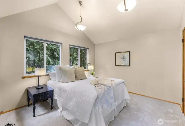The vaulted primary suite is a serene retreat with soft lighting, forest views, and cozy textures. Wake up to peaceful woodland surroundings and unwind in quiet privacy at day’s end.