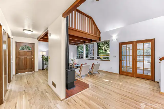 The home’s entryway flows effortlessly into the living room, revealing soaring ceilings, French doors to the sunroom, and large picture windows