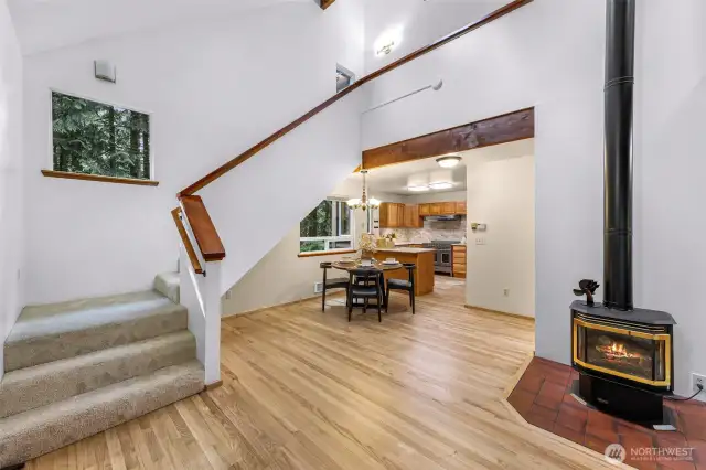A two-story ceiling and tall windows amplify the sense of airiness in this open stairwell and central living zone. The gas stove adds charm and warmth at the heart of it all.