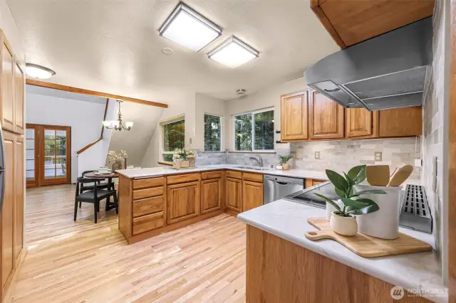 A wider angle of the kitchen reveals its full layout: quartz surfaces, stainless appliances, subway tile backsplash, and open sightlines to the dining nook and beyond.
