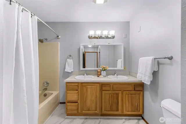 With dual sinks, a large vanity mirror, and soft ambient lighting, this main floor bathroom is perfect for sharing. Natural wood cabinetry and bright finishes create a warm and inviting feel.