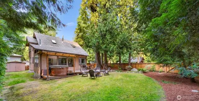 From another angle, the backyard’s design unfolds — inviting lawn space, a spacious deck, and tall cedar trees for year-round privacy. Perfect for summer evenings or quiet mornings.