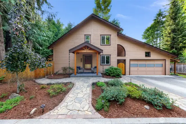 A closer view of the home's warm-toned exterior highlights its welcoming front porch, stone path, and thoughtful curb appeal. The newer roof and fresh landscaping boost first impressions.