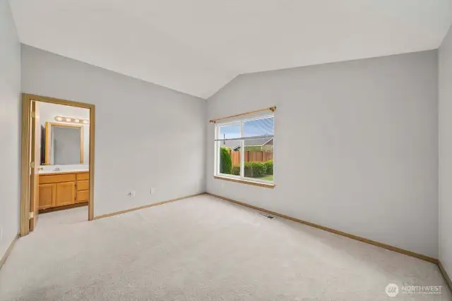 Spacious primary bedroom with vaulted ceilings, en suite bath with walk in shower and walk in closet