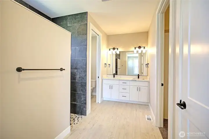 Beautiful primary suite includes heated tile floors, a custom walk-in shower, and generous closet space.