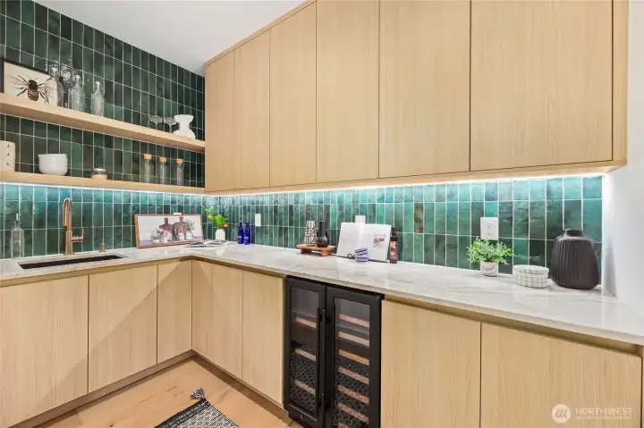 Luxury walk-in butler's pantry- complete  with wine fridge, sink, built in shelving and cabinetry tied together with stunning backsplash tile that goes from counter to ceiling